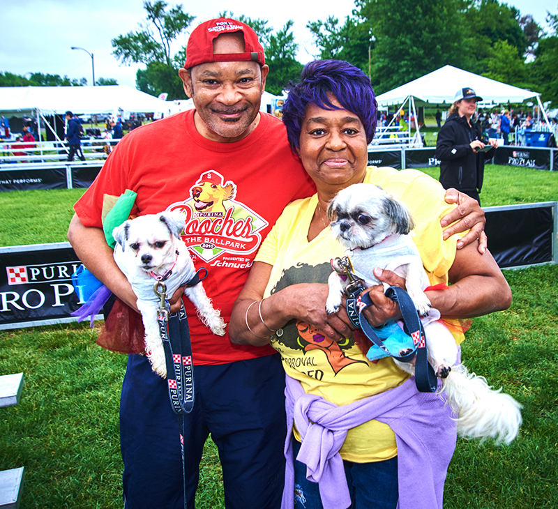 Man and woman holding dogs at Bark in the Park 2022